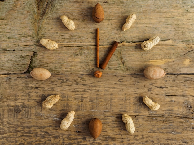 Orologio fatto di noci e cannella diversi sul tavolo di legno