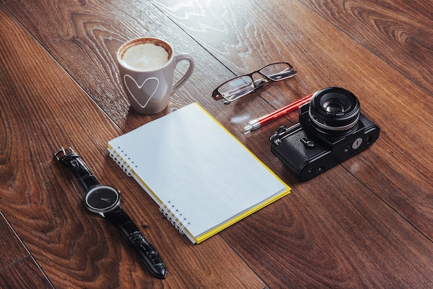 Orologio, macchina fotografica e taccuino su un marrone