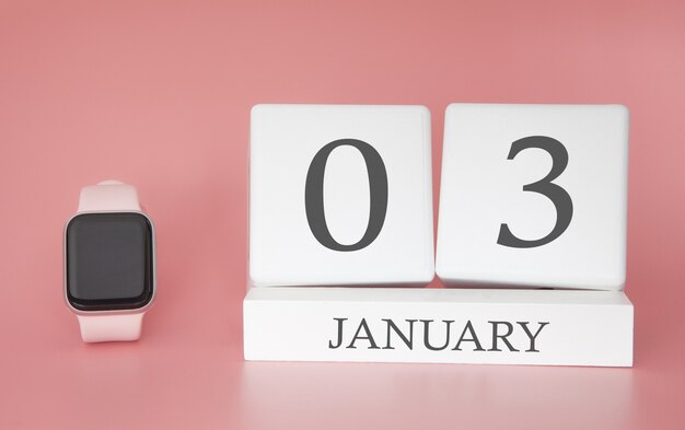 Orologio moderno con calendario cubo e data 03 gennaio su sfondo rosa. Vacanze invernali di concetto.