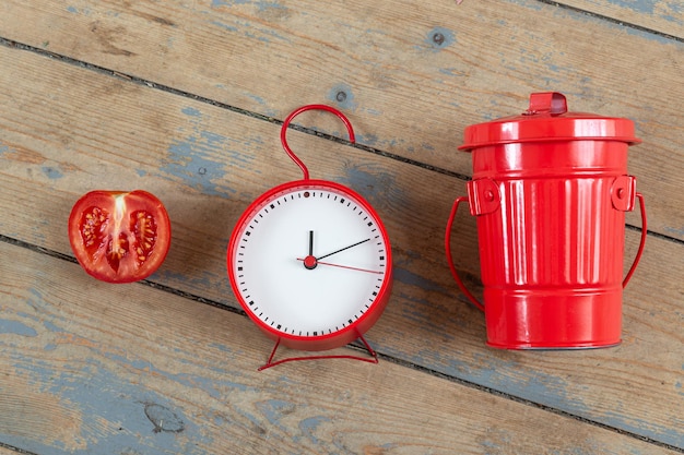 Orologio rosso mezzo pomodoro e tempo contenitore per la raccolta