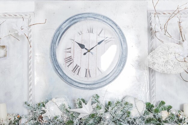 Orologio rotondo in legno sul muro bianco celebrazione decorazione domestica magica inverno decorato rami di albero di Natale e parete con grande sfondo orologio