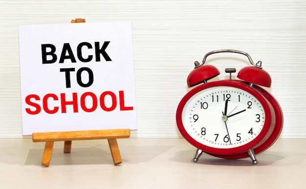 Orologio sveglia e rifornimenti scolastici su sfondo blu