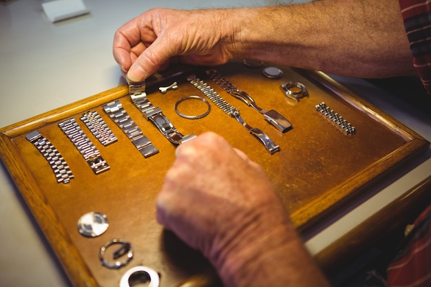 Orologista organizzando il cinturino dell'orologio su tavola di legno