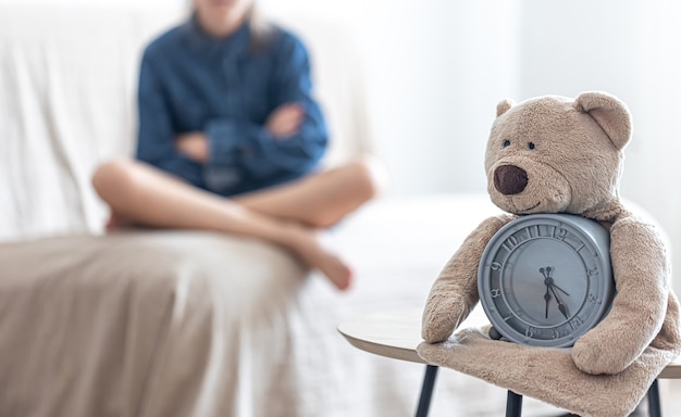 Orsacchiotto con sveglia su uno sfondo sfocato della stanza di una bambina.