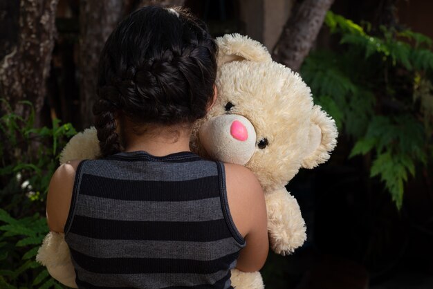 Orsacchiotto di peluche, bambino brasiliano che gioca con molto affetto con il suo orsacchiotto, fuoco selettivo.