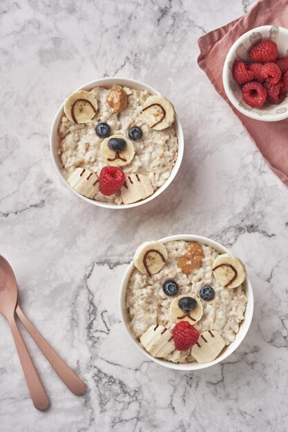 Orso di porridge di farina d'avena con banana e bacche divertente idea artistica per cibo per bambini vista dall'alto