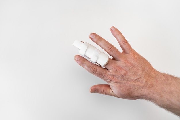 Ortesi per fissare il dito a portata di mano su uno sfondo bianco. langet per guarire le falangi delle dita, a causa di lesioni. accessori ortopedici. farmacia e attrezzature mediche.