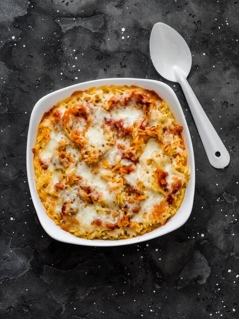 Orzo al forno con salsa di pomodoro e mozzarella in una teglia su uno sfondo scuro vista dall'alto