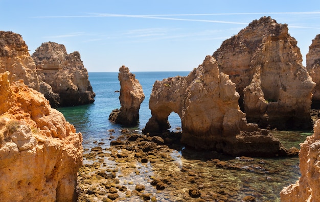 Oscilli gli arché della scogliera sulla linea costiera con l'acqua di mare del turchese sulla costa del Portogallo in Algarve