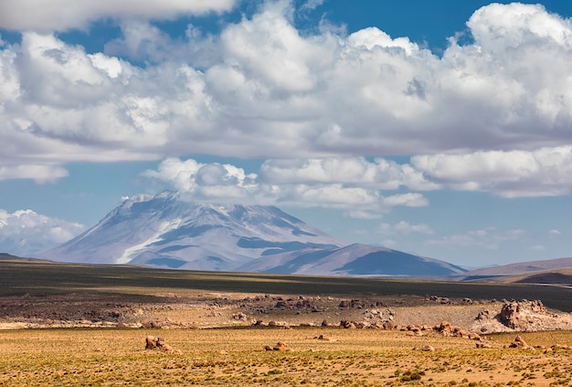 Osservi il deserto e il vulcano con le nuvole drammatiche in Potosi, Bolivia