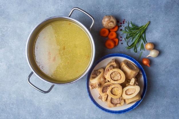 Osso bollito e brodo. Il brodo di ossa di manzo fatto in casa viene cotto in una pentola. Le ossa contengono collagene, che fornisce al corpo aminoacidi, che sono i mattoni delle proteine.