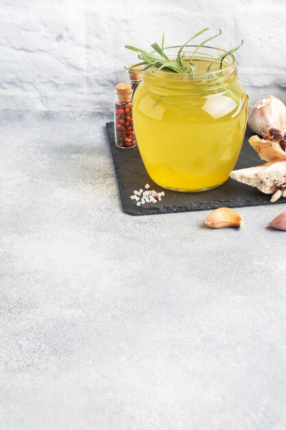 Osso di manzo fatto in casa e brodo vegetale con condimento alla curcuma in un bicchiere.