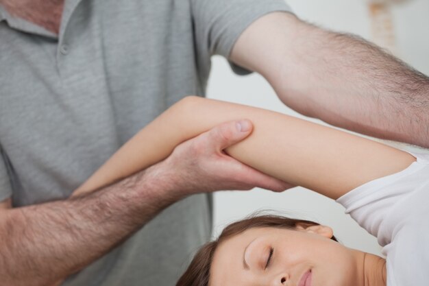 Osteopata tiene il braccio di una donna mentre massaggia il suo corpo