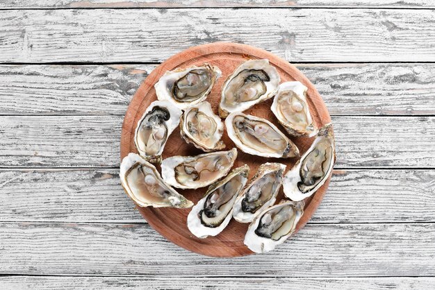 Ostriche con ghiaccio e limone su fondo di legno bianco Frutti di mare Vista dall'alto Spazio libero per la copia