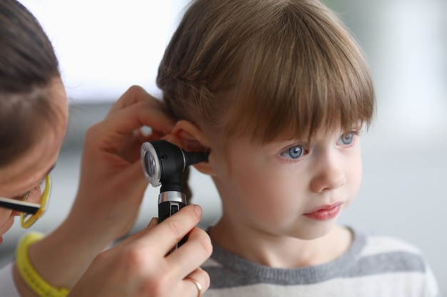 Otorinolaringoiatra esamina l'orecchio della bambina con l'otoscopio. Adenoidite come causa di otite media nel concetto di bambini.