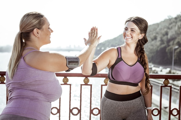 Ottimo allenamento. Felici belle donne che si danno il cinque a vicenda mentre sono in piedi sul ponte