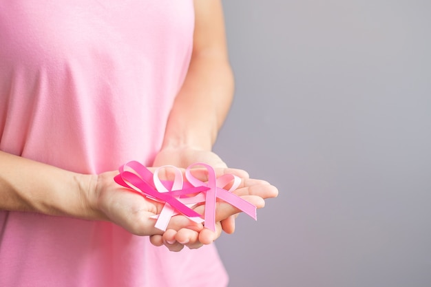 Ottobre Mese della consapevolezza del cancro al seno, donna anziana in maglietta rosa con la mano che tiene il nastro rosa per sostenere le persone che vivono e le malattie. Concetto di giornata internazionale delle donne, della madre e del cancro del mondo