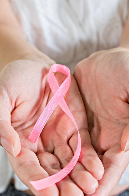 Ottobre Mese della consapevolezza del cancro al seno Donna in abito bianco con la mano che tiene il nastro rosa