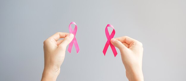 Ottobre mese di sensibilizzazione sul cancro al seno, mano che tiene il nastro rosa per sostenere le persone che vivono e le malattie. Concetto di giornata internazionale delle donne, della madre e del cancro del mondo