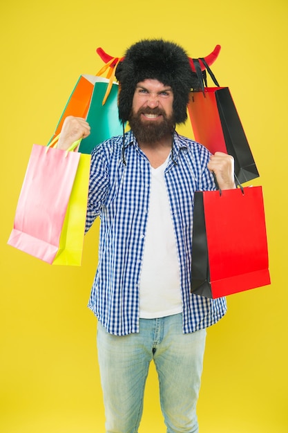 Pacchetti completi di articoli Uomo faccia da matto indossare cappello toro con le corna Hipster dipendente dallo shopping o maniaco dello shopping Concetto di shopping Ragazzo shopping sconto stagione dei saldi Negozio di animali e veterinario Selvaggio per lo shopping