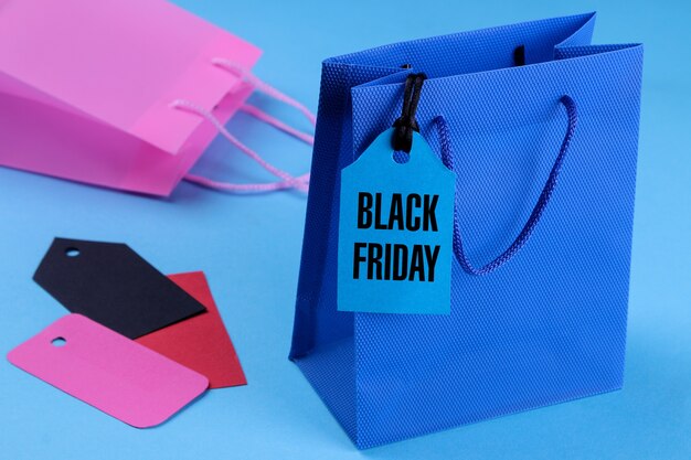 Pacchetto blu per lo shopping in primo piano con un cartellino del prezzo con la scritta Black Friday. su sfondo blu