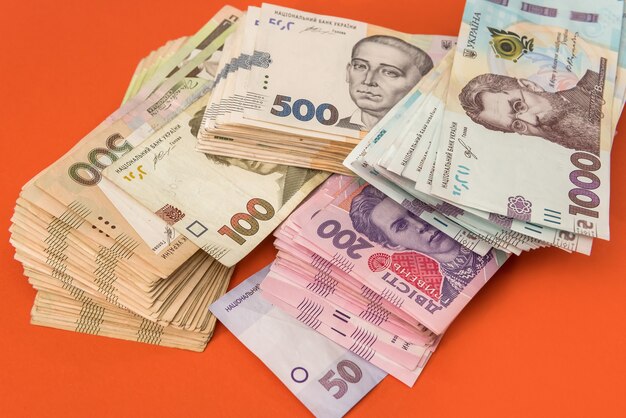 Pacco di denaro ucraino isolato su rosso, pila di grivna uah, 200 500 e nuova banconota da 1000. concetto di denaro