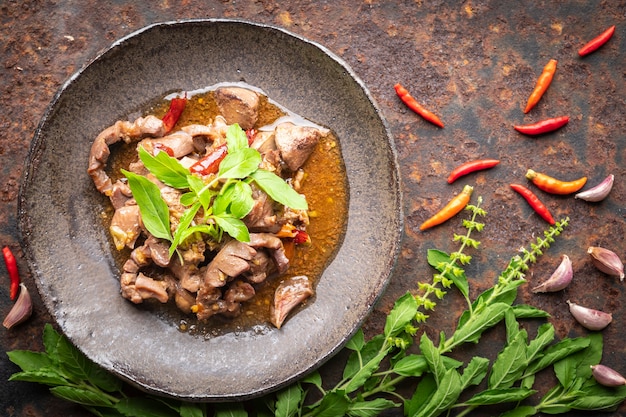 Pad Ka Prao Kruang Nai Gai, cibo tailandese, basilico mescolare frattaglie di pollo fritto, varietà di carne, carne cotta o organi in piatto stile wabi sabi su sfondo texture arrugginito, vista dall'alto