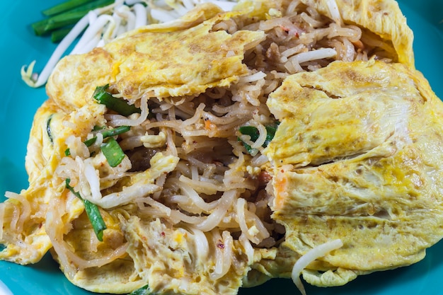 Pad thai, tagliatelle saltate in padella con cibo tailandese con gamberetti. Avvolgere le uova sulla piastra bianca