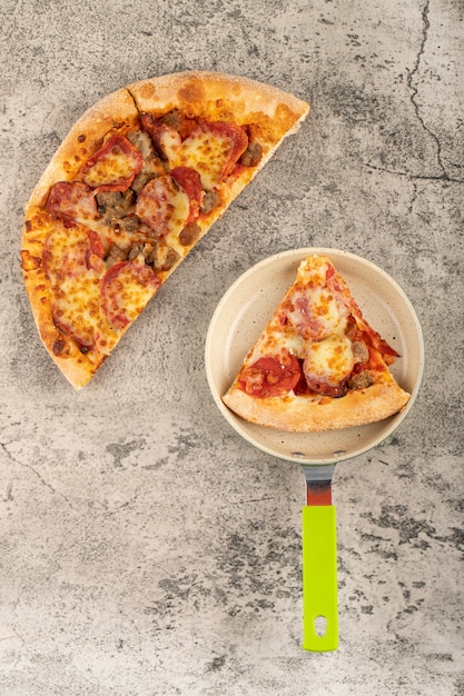 Padella con fetta di gustosa pizza sul tavolo di pietra.