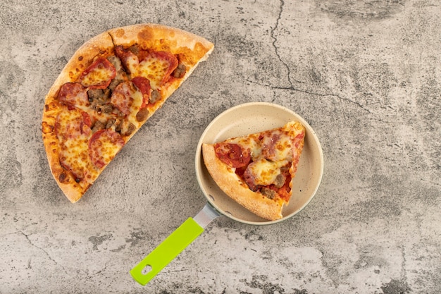 Padella con fetta di gustosa pizza sul tavolo di pietra.