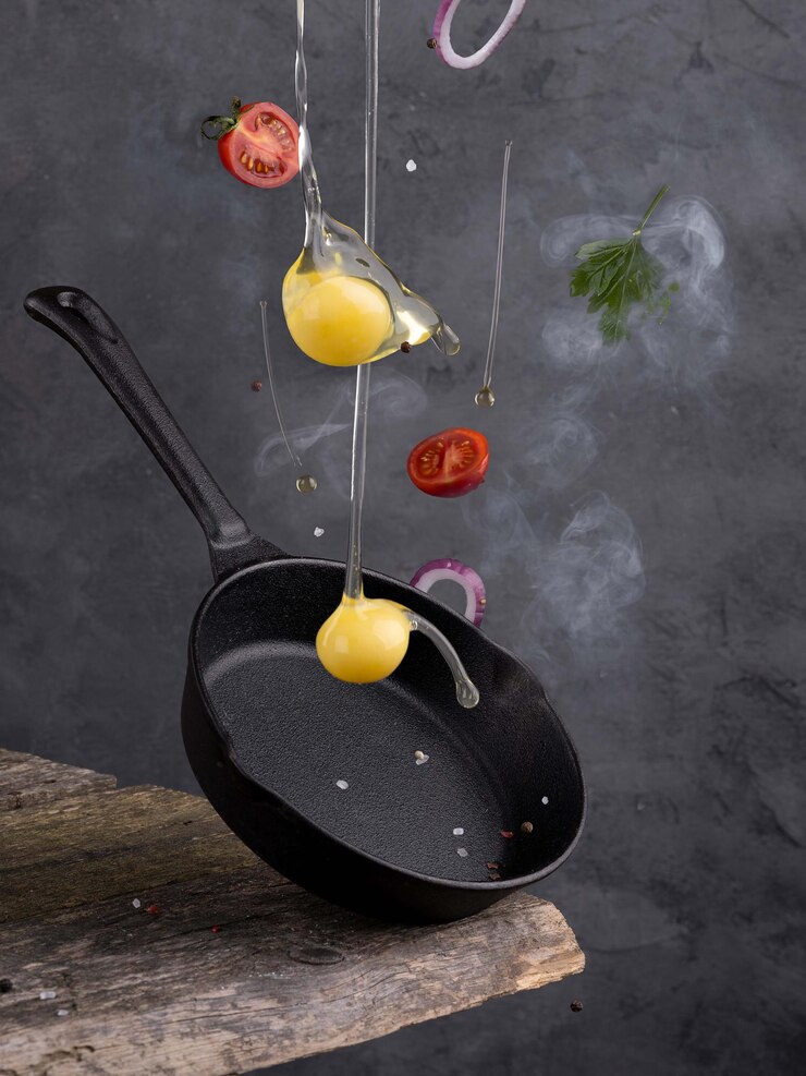 Padella con guscio d'uovo crudo di levitazione sul tavolo di legno.