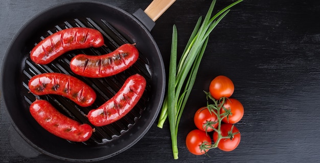 Padella con salsicce fritte e pomodori con cipolle