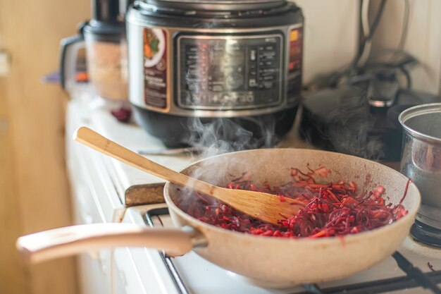 Padella con verdure per primo piatto su sfondo di multi-fornello. Cucinare il borscht in un multi-fornello.