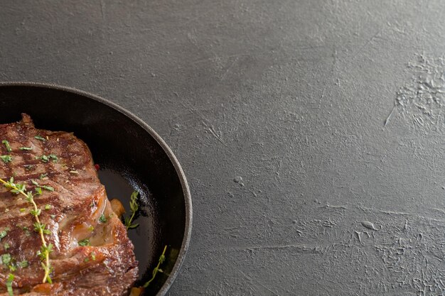 Padella di carne alla griglia guarnita con erbe aromatiche Pasto del ristorante fatto in casa Copia spazio su sfondo nero