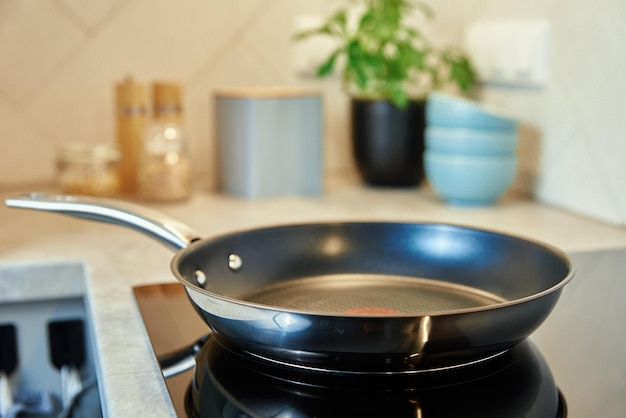 Padella in acciaio in cucina su piano cottura elettrico a induzione, elettrodomestico da cucina moderno