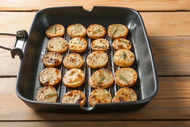 Padella per grigliare con deliziose fette di patate al forno sul tavolo