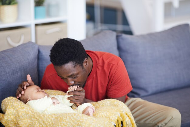 Padre africano che bacia la mano del neonato mentre dorme sono nel soggiorno di casa