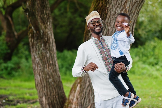 Padre africano con figlio in abiti tradizionali al parco.