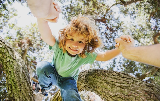 Padre aiutando il figlio padri mano e aiutando il figlio a scalare la protezione del bambino albero