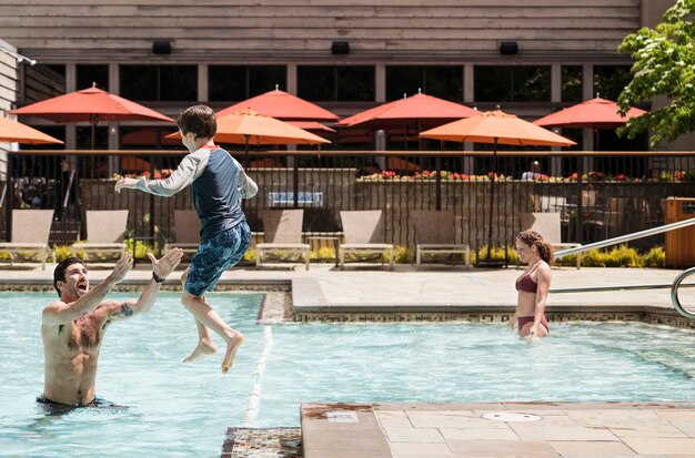 Padre alzando le braccia e suo figlio che salta in piscina