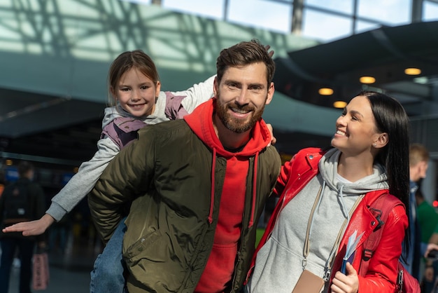 Padre barbuto che cavalca la figlia sulla schiena Ritratto di ragazza felice sulle spalle dell'uomo sulle spalle Ragazza vola alza le mani Famiglia che gioca all'aeroporto Emozioni felici