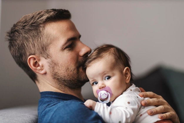 Padre che abbraccia la bambina e la bacia in testa