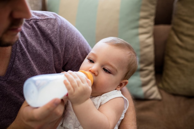 Padre che alimenta il latte alla neonata a casa