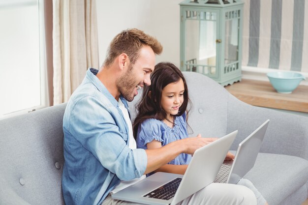 Padre che assiste figlia nell'uso del computer portatile