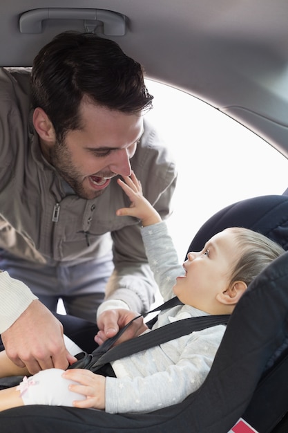 Padre che fissa il bambino nel seggiolino