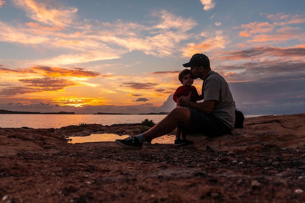 Padre che gioca con il figlio piccolo su una spiaggia al tramonto nell'isola di San Antonio Abad Ibiza