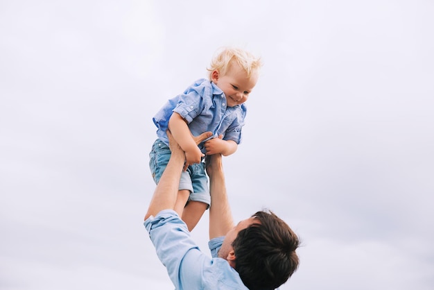 Padre che gioca con suo figlio contro il cielo Uomo e bambino ragazzo Sfondo familiare Papà e suo figlio si divertono in una giornata estiva sulla natura