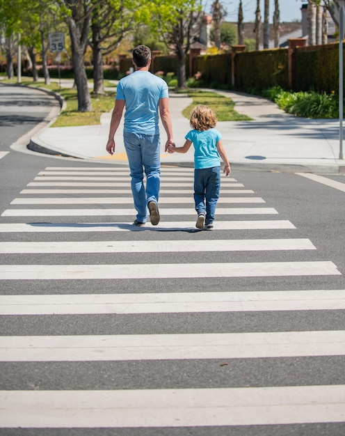 Padre che guida suo figlio attraverso le strisce pedonali insieme