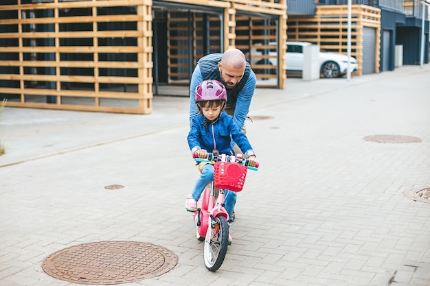 Padre che insegna alla sua piccola figlia ad andare in bicicletta Attività familiari insieme