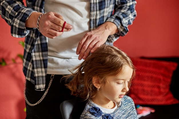 Padre che pettina, spazzola i capelli di sua figlia a casa